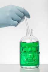 A hand in laboratory gloves mixes chemistry. Liquid in laboratory bottles. Scientific biochemical laboratory. Colorful liquid.