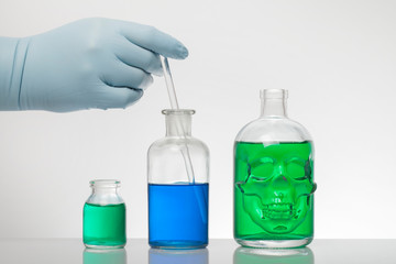 A hand in laboratory gloves mixes chemistry. Liquid in laboratory bottles. Scientific biochemical...