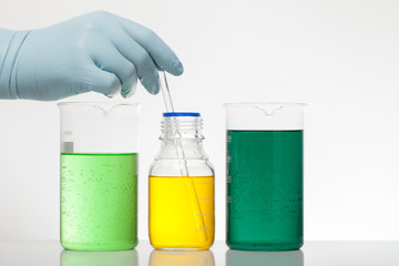 A hand in laboratory gloves mixes chemistry. Liquid in laboratory bottles. Scientific biochemical...
