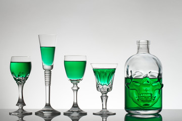 A skull bottle and crystal glasses with a liquid, alcohol drink.