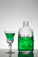 A skull bottle and crystal glasses with a liquid, alcohol drink.