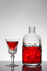 A skull bottle and crystal glasses with a liquid, alcohol drink.