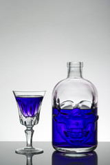 A skull bottle and crystal glasses with a liquid, alcohol drink.