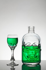 A skull bottle and crystal glasses with a liquid, alcohol drink.