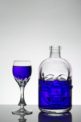 A skull bottle and crystal glasses with a liquid, alcohol drink.