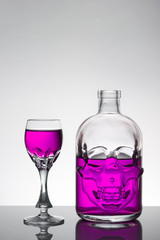 A skull bottle and crystal glasses with a liquid, alcohol drink.