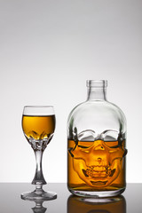 A skull bottle and crystal glasses with a liquid, alcohol drink.