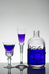 A skull bottle and crystal glasses with a liquid, alcohol drink.
