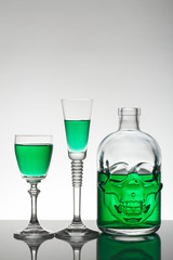 A skull bottle and crystal glasses with a liquid, alcohol drink.