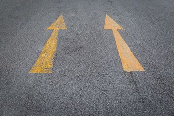 Two yellow arrows old and new  directionon asphalt road