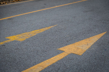 Two yellow arrows old and new  directionon asphalt road