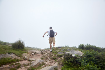 Man runing on the top of hill on foggy summer day. Hiking trail in the Pyrenees. La Rhune mountain, France