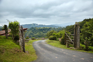 Fototapeta na wymiar Countryside in southern France in the foothills of the Pyrenees mountains. Wooden fence with gate and rural road