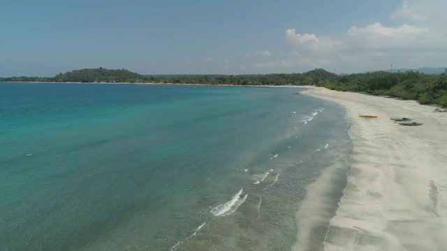 Beautiful tropical beach Cabugao with white sand and palm trees in the Philippines, Luzon. Aerial view of coast with beach and turquoise water.