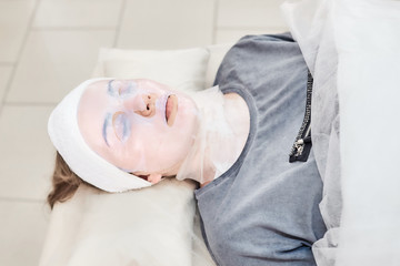 Obraz na płótnie Canvas Cosmetic skincare procedure. Biocellulose Fiber Lifting Mask. Facial treatment. Woman in a beauty salon