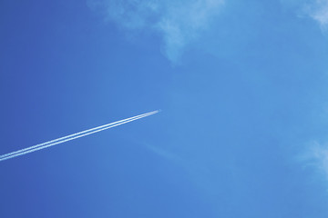 Plane in the blue sky with white clouds. The aircraft leaves traces