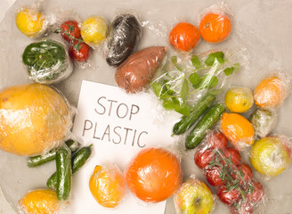 many different fruits and vegetables are wrapped in plastic foil, packed on concrete background