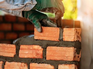 worker installing bricks wall in process of building