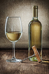bottle and glass with white wine and corcksrew