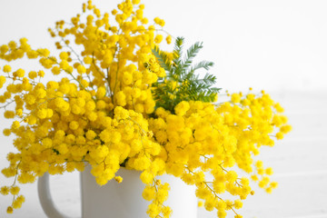 Bouquet of mimosa flowers on white wooden background. Springtime.