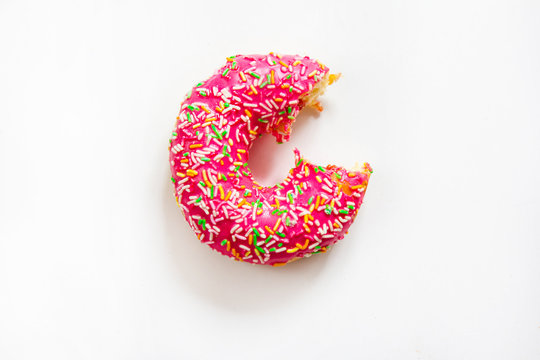 One pink bitten donut cake at white background