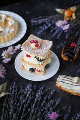 Tea and sweets on a dark background, Mille-feuille, Eclairs, Tart, Decorative with flowers, Selective focus, Closeup