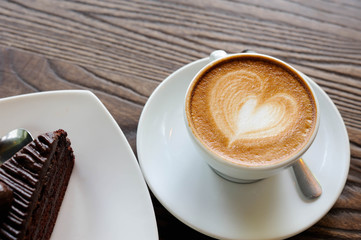 Cappuccino coffee in white cup lay on wooden table,Relax time with coffee and chocolate cake,Art of coffee,Chocolate cake put on wooden table