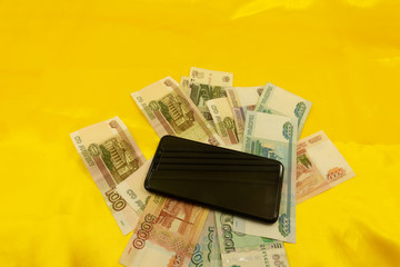 euro coins paper money and mobile phone on a yellow background