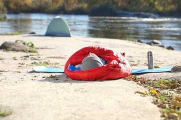 Male camper lying in sleeping bag on wild beach
