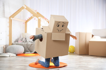 Cute little child wearing cardboard costume in bedroom