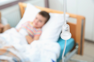 Little child with intravenous infusion in hospital bed, focus on drip chamber