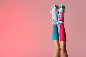 Woman with vintage roller skates on color background, closeup. Space for text