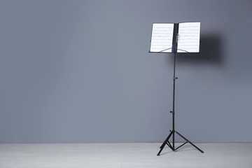 Note stand with music sheets near grey wall indoors. Space for text - obrazy, fototapety, plakaty