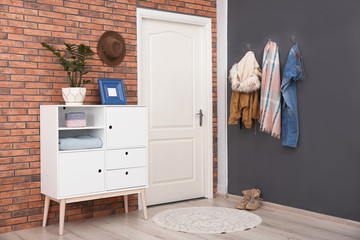 Fototapeta na wymiar Modern hallway interior with stylish cabinet and clothes on wall