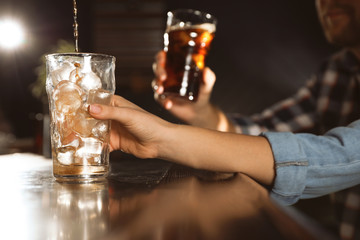 People with cola in glasses at bar counter indoors, closeup. Pouring beverage