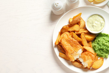 British Traditional Fish and potato chips on wooden background, flat lay. Space for text