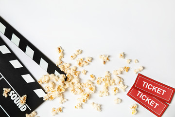 Clapperboard, popcorn and tickets isolated on white, top view. Cinema snack