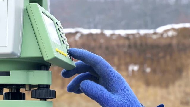 Close-up finger that pushes the Surveyor buttons at work measuring the distance. The concept of winter construction
