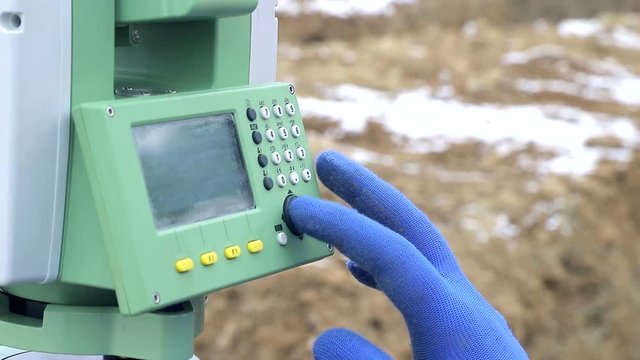 Close-up finger that pushes the Surveyor buttons at work measuring the distance. The concept of winter construction