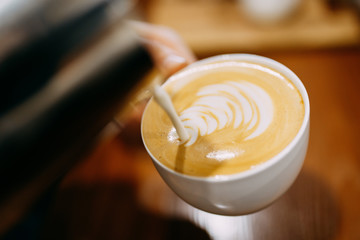 Barista makes coffee. Latte in the white cup.