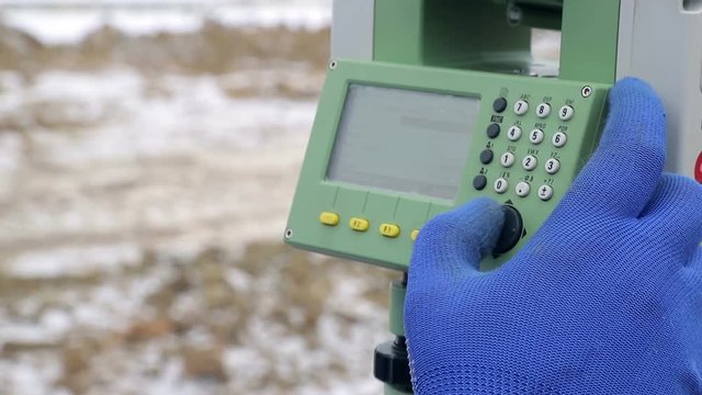 Close-up finger that pushes the Surveyor buttons at work measuring the distance. The concept of winter construction
