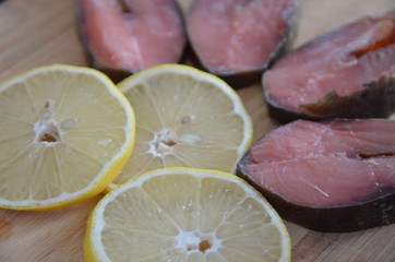 Red fish and lemon slices on wooden background