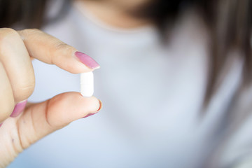 closeup woman hand holding one antibiotic pill
