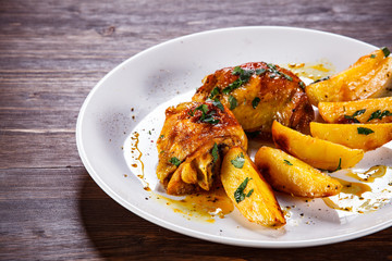 Grilled chicken thighs with baked potatoes on wooden table