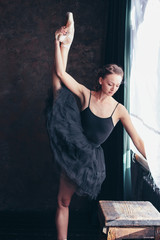 Fototapeta na wymiar Candid portrait of Ballet dancer ballerina in black dress posing front of the window