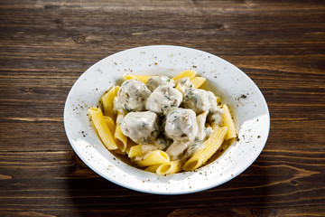 Pasta with meatballs and sauce on wooden table