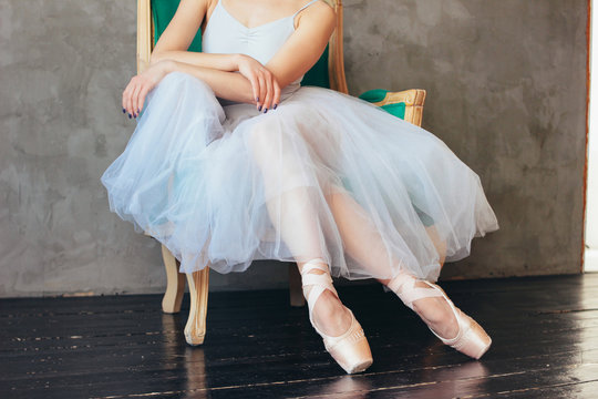 The ballerina ballet dancer in tutu skirt and pointe shous sitting on the classic chair