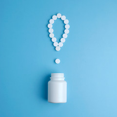 The exclamation mark of the pills. Exclamation point. White pills on a blue background. Important information on medical topics. Pill exclamation mark on blue background.