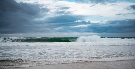 View Atlantic ocean coast.  A wave runs to the sandy beach. Blue sky with clouds.