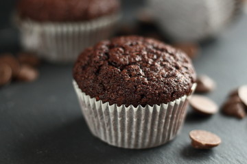 Chocolate homemade cupcakes muffins on a black background with chocolate drops in the background. Bakery style. Dark food photo